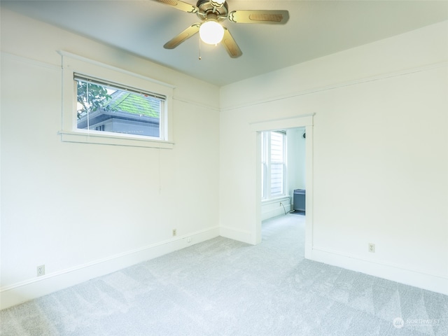 spare room with light carpet, a wealth of natural light, and ceiling fan