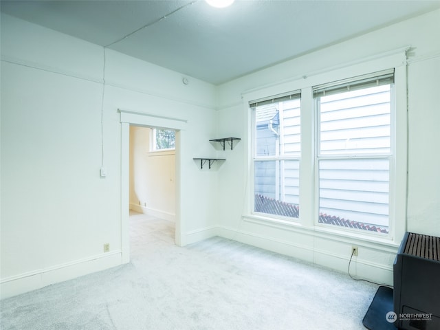 empty room featuring heating unit and light carpet