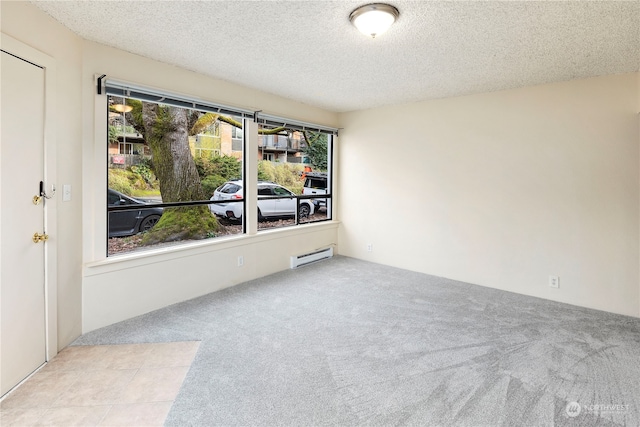 spare room featuring light carpet, a textured ceiling, and a wealth of natural light