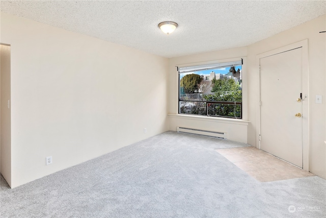 carpeted spare room featuring a baseboard heating unit and a textured ceiling