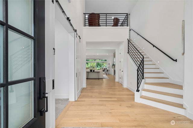 foyer entrance with light wood-type flooring, a high ceiling, and a barn door