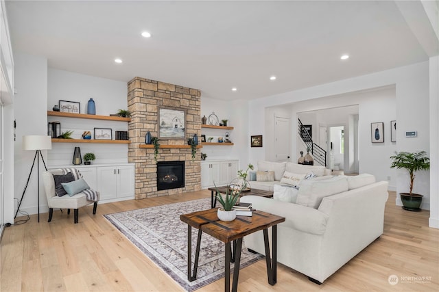 living room with a stone fireplace and light wood-type flooring