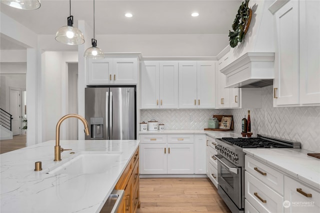 kitchen with light wood-type flooring, sink, white cabinets, stainless steel appliances, and light stone countertops