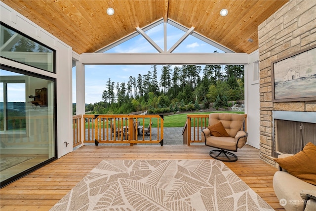 sunroom / solarium with vaulted ceiling, an outdoor stone fireplace, and wooden ceiling