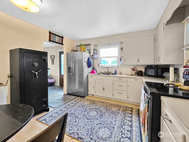 kitchen with appliances with stainless steel finishes, white cabinetry, and sink