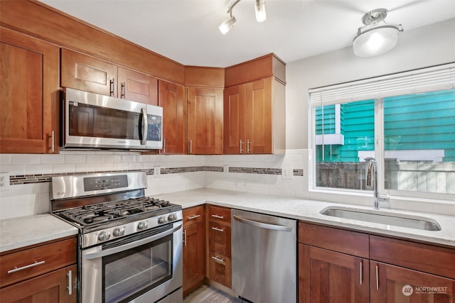 kitchen with light stone countertops, appliances with stainless steel finishes, sink, and decorative backsplash