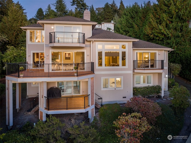 back house at dusk featuring a balcony