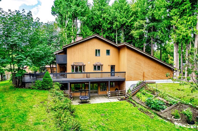 rear view of property featuring a patio area, a yard, and a deck