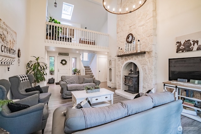 living room featuring hardwood / wood-style flooring, a wood stove, a towering ceiling, and a skylight