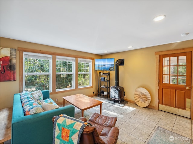 living room featuring a wood stove, plenty of natural light, and light tile patterned flooring