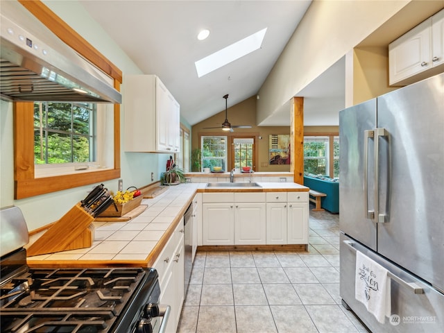 kitchen featuring ceiling fan, white cabinets, island exhaust hood, stainless steel appliances, and tile countertops