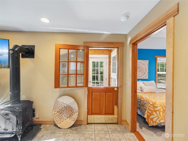 entrance foyer with light tile patterned floors, a wood stove, and plenty of natural light