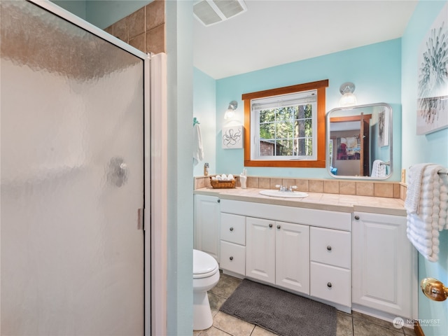 bathroom featuring vanity, toilet, a shower with door, and tile patterned floors