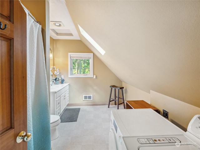 bathroom with separate washer and dryer, lofted ceiling with skylight, vanity, and toilet