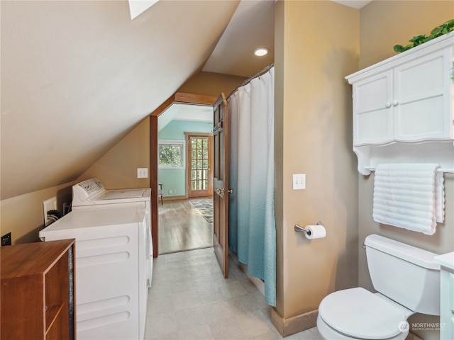 bathroom with vanity, toilet, washer and dryer, hardwood / wood-style flooring, and vaulted ceiling