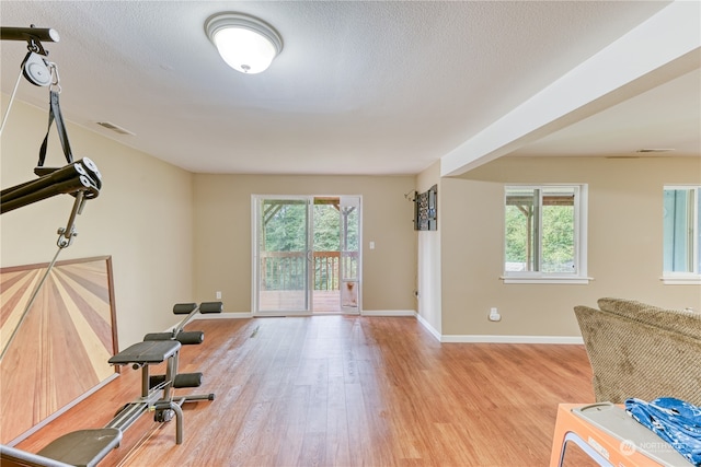 home office featuring light hardwood / wood-style flooring, a wealth of natural light, and a textured ceiling