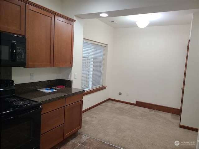 kitchen featuring dark stone counters, dark colored carpet, and black appliances