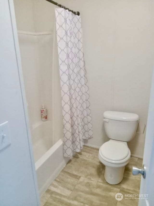 bathroom with shower / bathtub combination with curtain and toilet