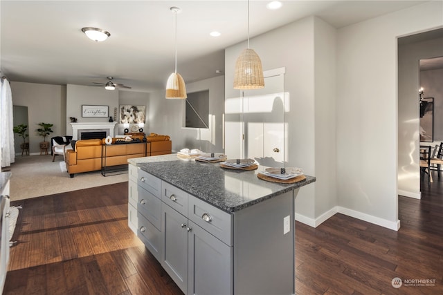 kitchen with dark stone countertops, pendant lighting, dark wood-type flooring, and gray cabinetry