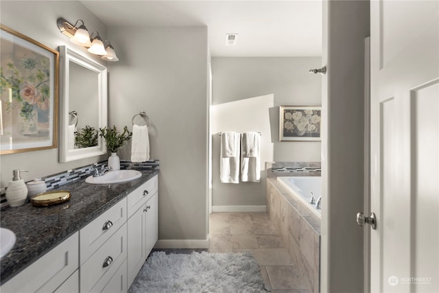 bathroom featuring a relaxing tiled tub and vanity