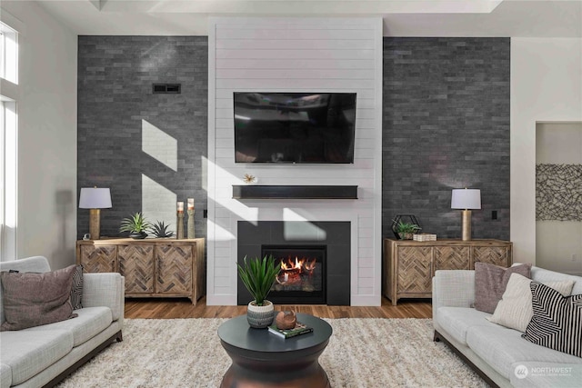 living room featuring wood-type flooring and a large fireplace