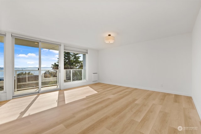 empty room with light wood-type flooring and a water view