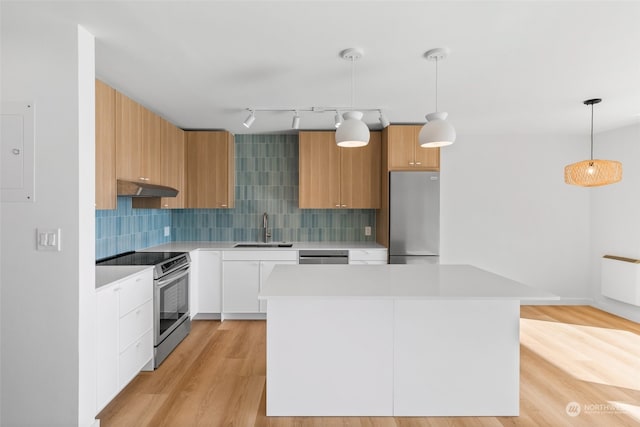 kitchen featuring light wood-type flooring, sink, white cabinets, hanging light fixtures, and appliances with stainless steel finishes