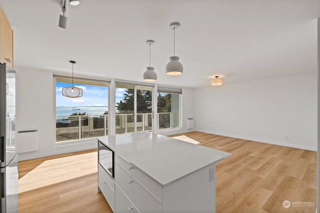 kitchen featuring white cabinets, a kitchen island, an inviting chandelier, light hardwood / wood-style flooring, and decorative light fixtures