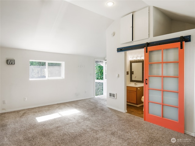 unfurnished living room featuring high vaulted ceiling, sink, carpet floors, and a barn door