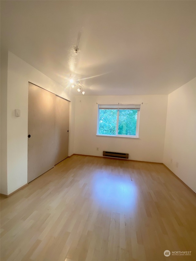 interior space with light wood-type flooring and a baseboard heating unit