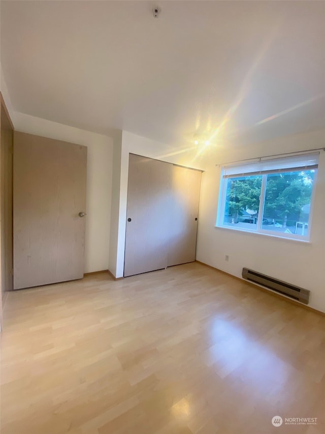 empty room featuring baseboard heating and light wood-type flooring