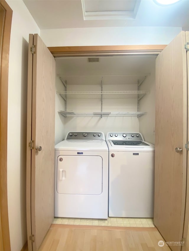 washroom with light hardwood / wood-style flooring and washing machine and dryer