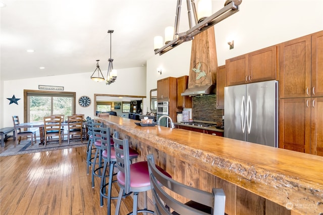 kitchen featuring pendant lighting, butcher block countertops, dark wood-type flooring, appliances with stainless steel finishes, and decorative backsplash