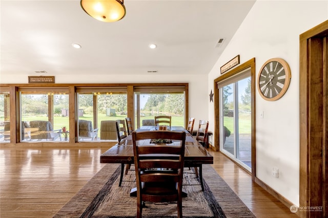 dining room with vaulted ceiling, hardwood / wood-style flooring, and plenty of natural light