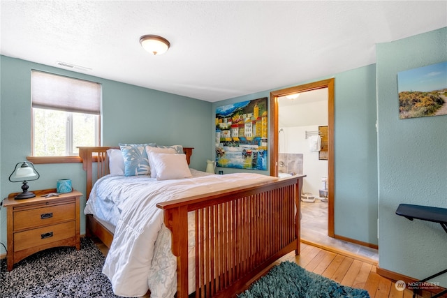 bedroom featuring ensuite bathroom and hardwood / wood-style flooring