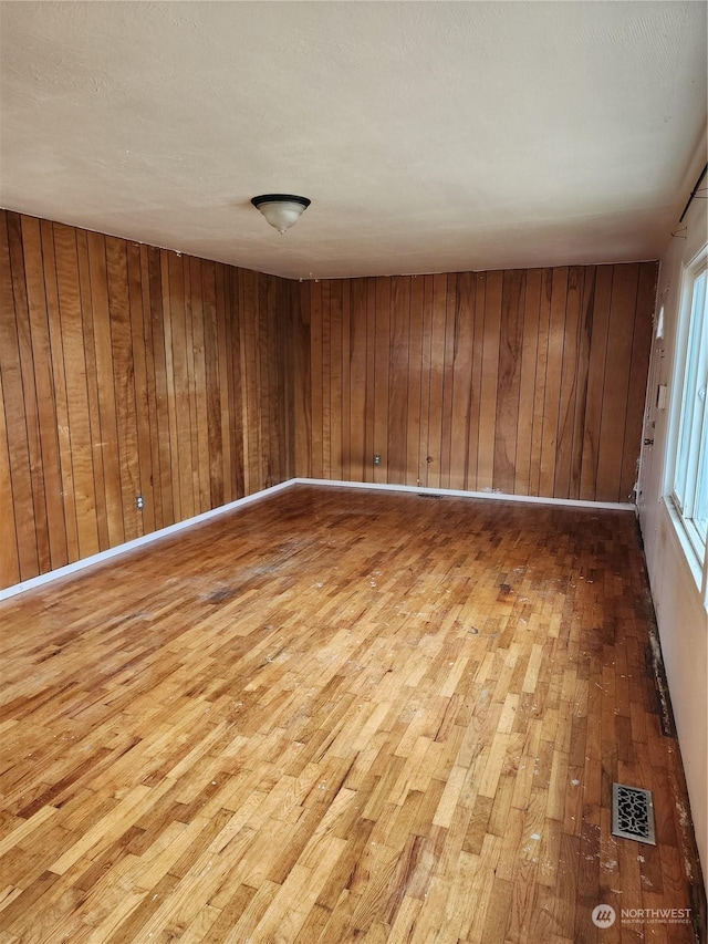 unfurnished room featuring visible vents, wooden walls, and wood-type flooring