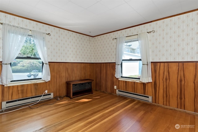 3224 SW Scenic Heights St, Oak Harbor, WA 98277 - unfurnished living room with a baseboard heating unit, wood-type flooring, a wainscoted wall, healthy amount of natural light, and crown molding