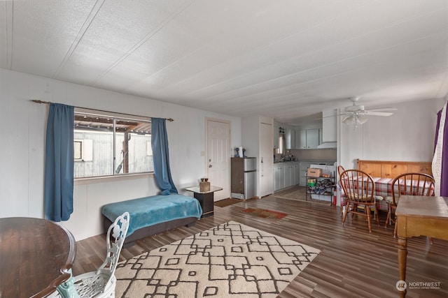 living room with wood walls, ceiling fan, dark hardwood / wood-style floors, and a textured ceiling