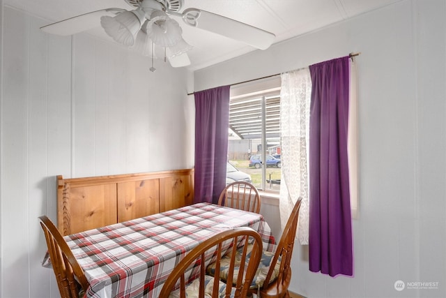 dining space with wood walls and ceiling fan