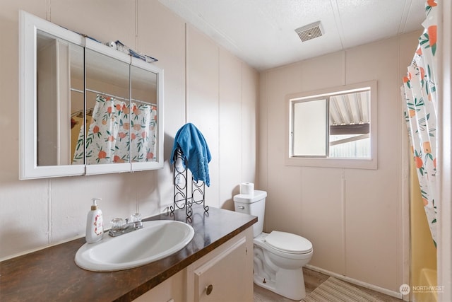 bathroom featuring a textured ceiling, vanity, and toilet