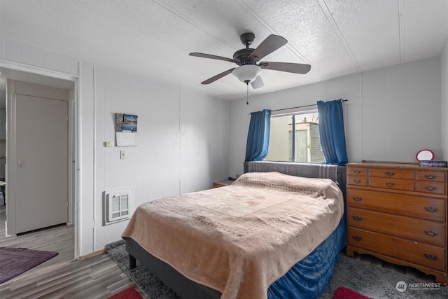 bedroom with wooden walls, ceiling fan, hardwood / wood-style floors, and a textured ceiling