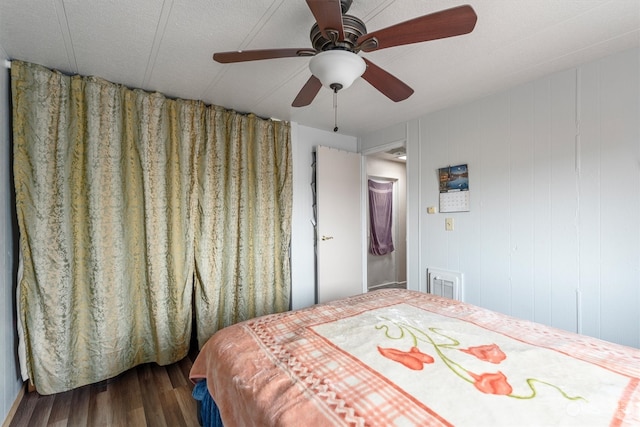 bedroom featuring wood-type flooring, wood walls, and ceiling fan