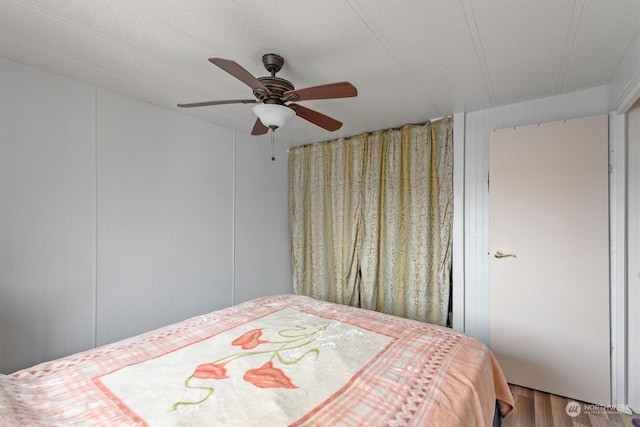 bedroom with wood walls, ceiling fan, and hardwood / wood-style floors