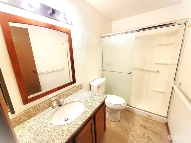 bathroom with a shower with door, vanity, and toilet