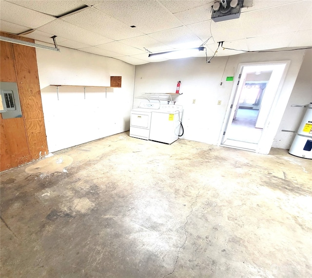 garage featuring washing machine and clothes dryer, a garage door opener, water heater, and electric panel