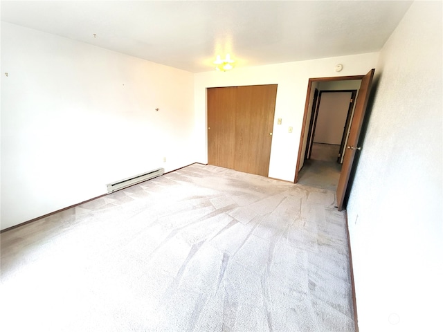 unfurnished bedroom with light colored carpet, a baseboard radiator, and a closet