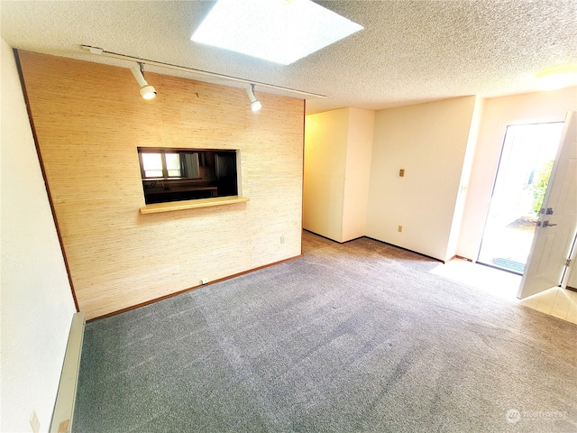 unfurnished living room featuring a textured ceiling, track lighting, and a skylight