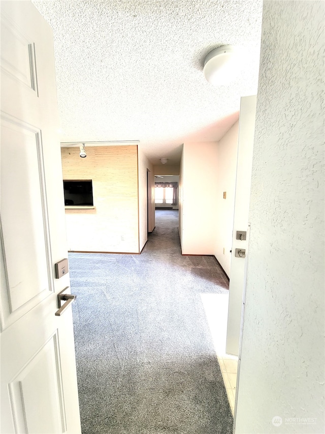 hallway with light colored carpet and a textured ceiling