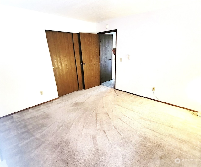 unfurnished bedroom featuring light carpet and a closet