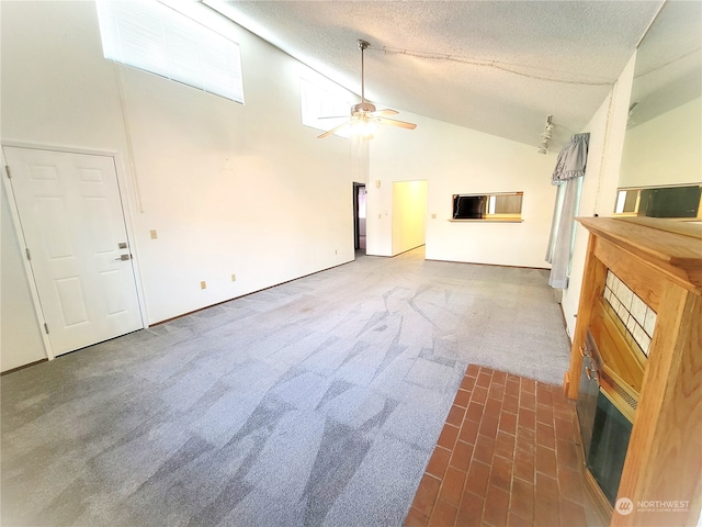 unfurnished living room with ceiling fan, dark carpet, a textured ceiling, and high vaulted ceiling